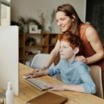 A mother helps her son with online learning on a home computer.