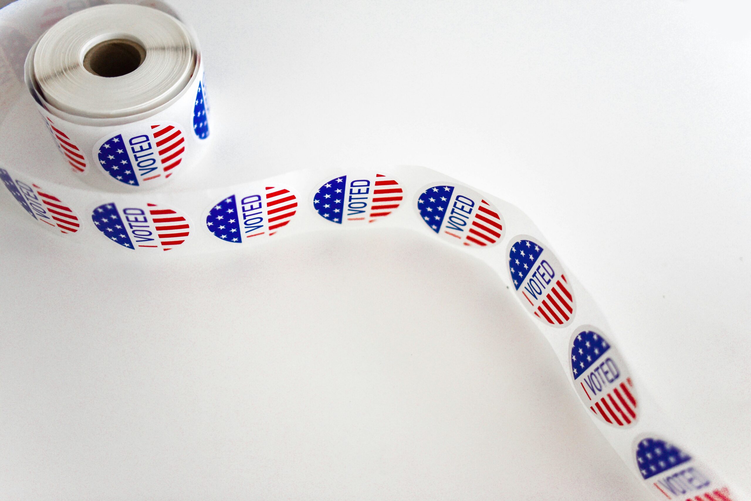 Close-up of a roll of 'I Voted' stickers featuring the American flag design on a white background.