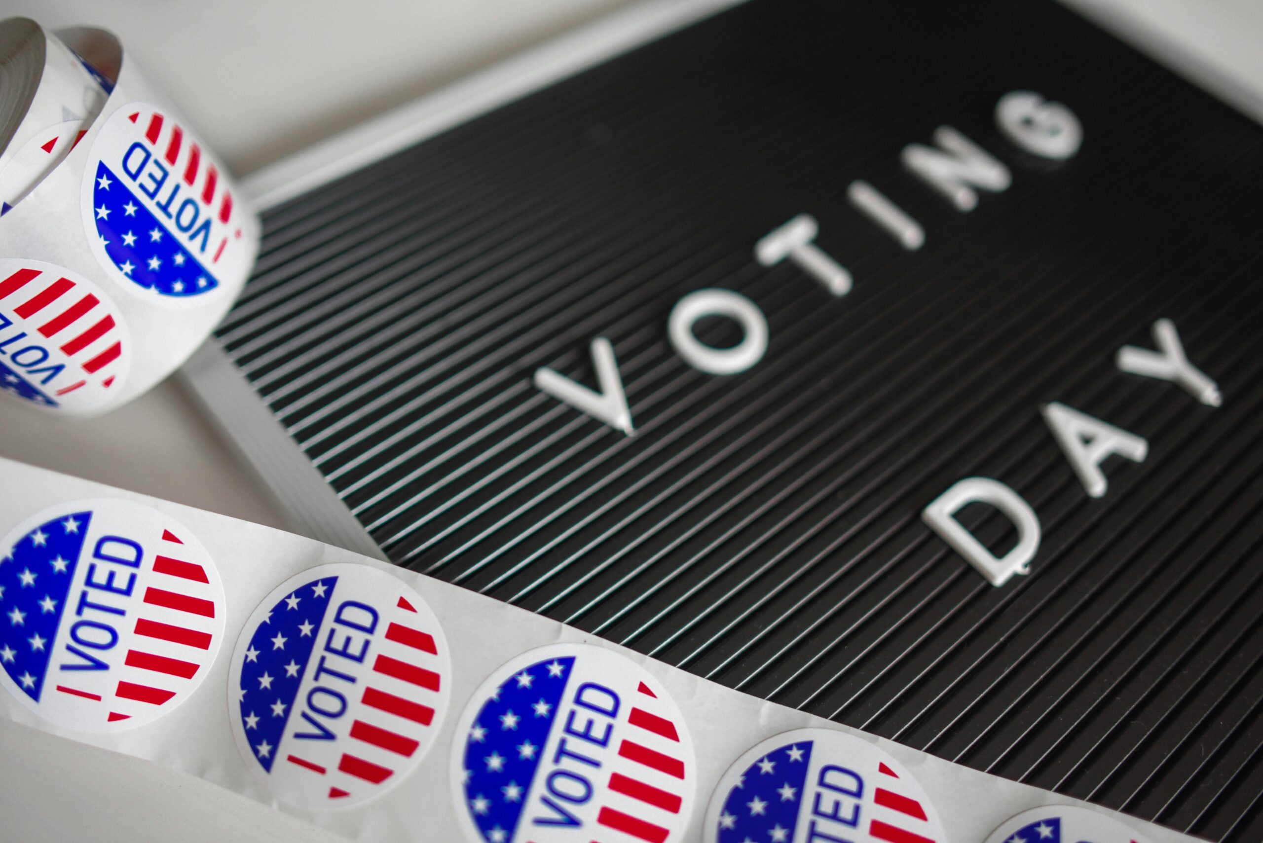 I Voted stickers with an American flag design and Voting Day sign symbolize U.S. electoral participation.