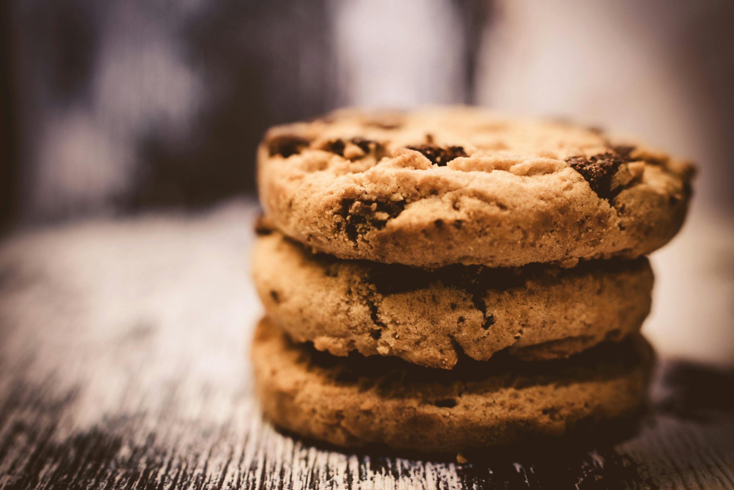 A macro shot of freshly baked stacked chocolate chip cookies creates a cozy dessert vibe.