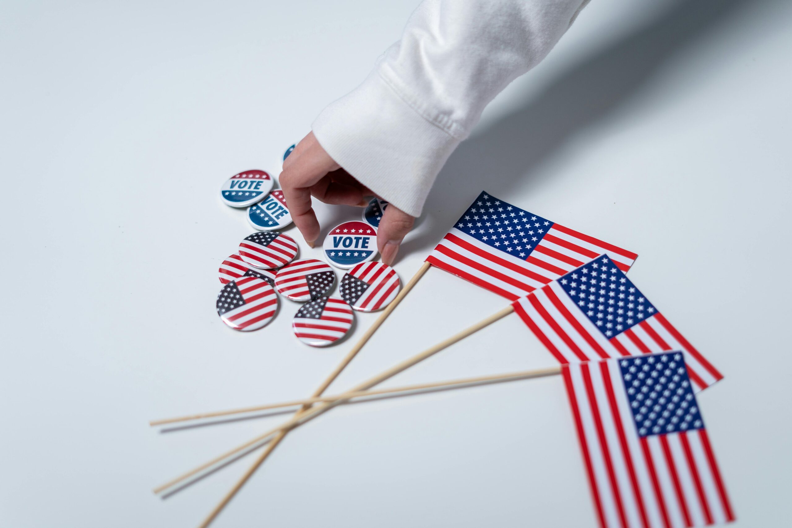 Hand reaching for voting buttons and USA flags, symbolizing patriotism and democratic duty.